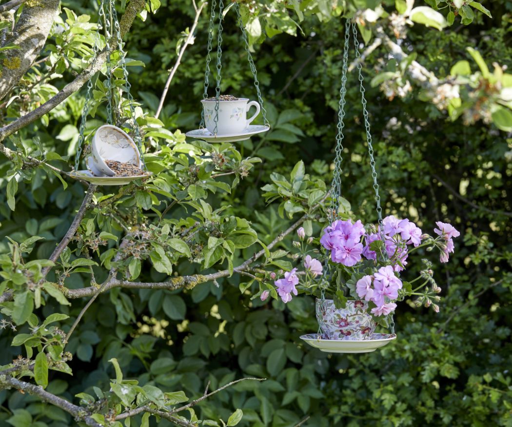 Upcycling Blumenampel aus Vintage Tasse und Untertasse mit lilafarbener Geranie in Garten