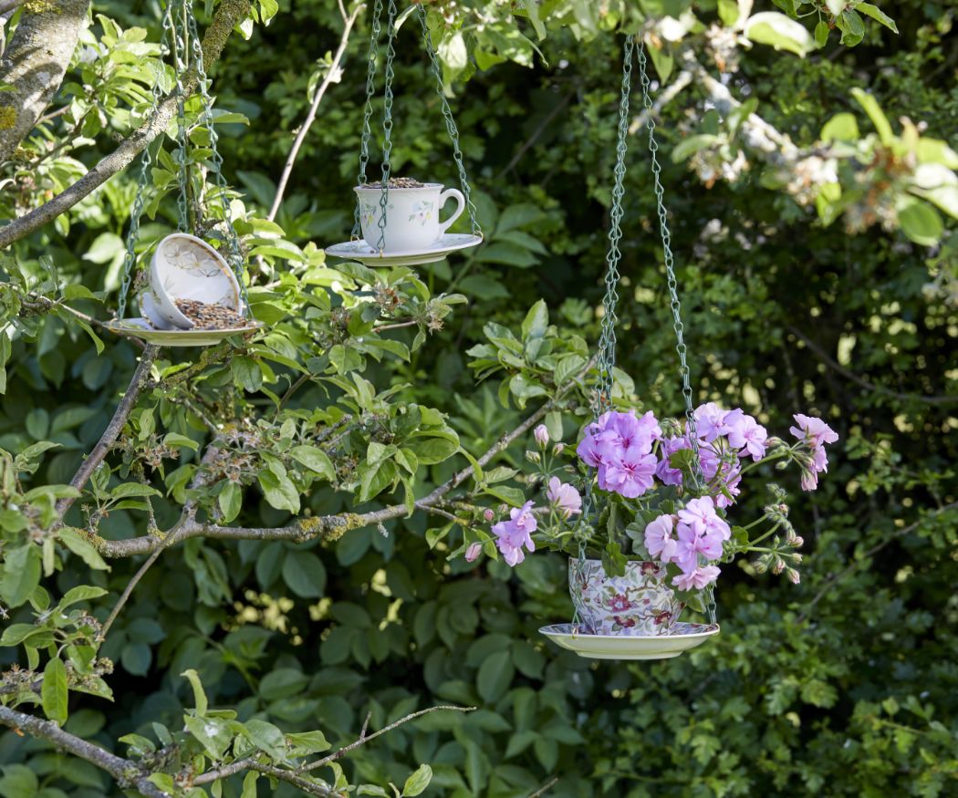 Upcycling Blumenampel aus Vintage Tasse und Untertasse mit lilafarbener Geranie in Garten